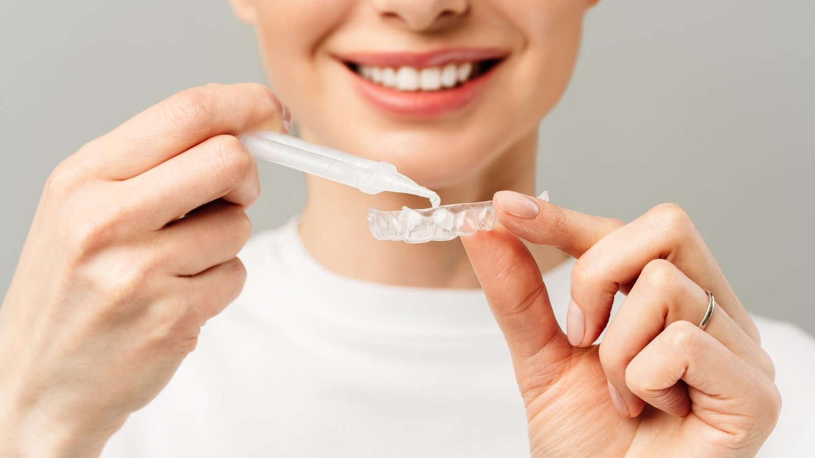 girl trying to whiten her teeth with a whitening product in an invisible tray
