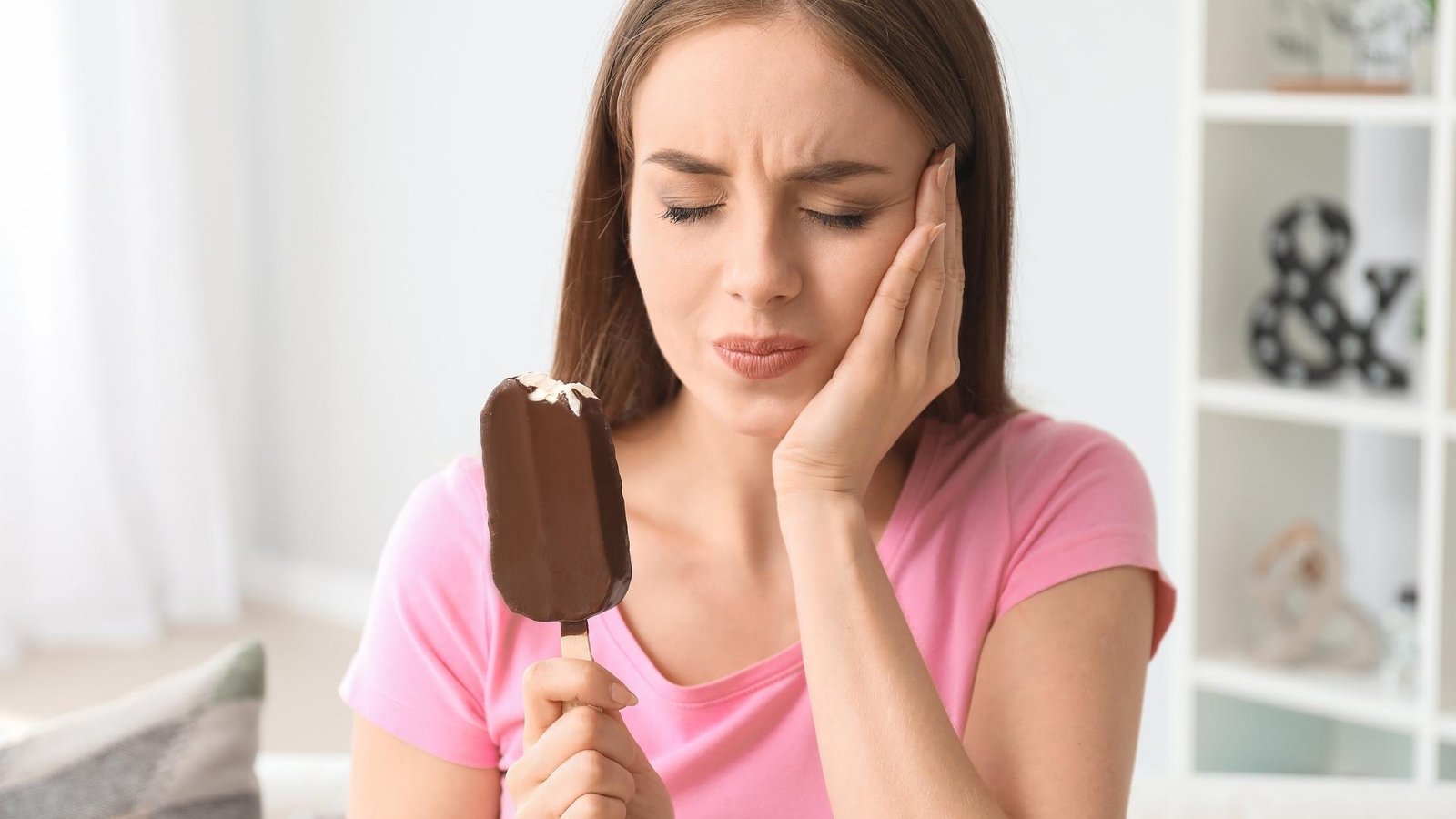 woman reacting to tooth sensitivity caused by an ice cream